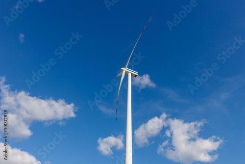 Turbina wiatrowa na tle nieba z chmurami z perspektywy poziomej z profilu.
Ekologiczne rozwiązania energetyczne źródeł odnawialnych.    photo