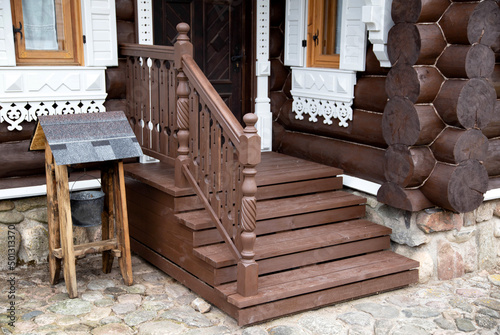 Wooden porch with steps and a door to a log cabin. Village houses architecture, close-up