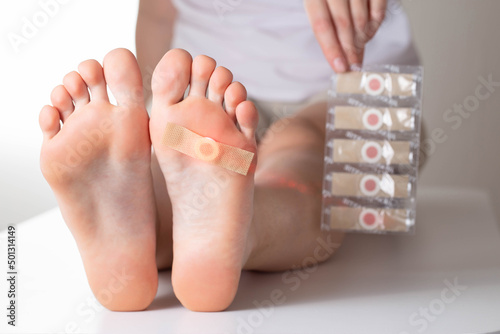 The girl holds in her hand a set of medical plasters for plantar warts. Treatment of calluses on the feet