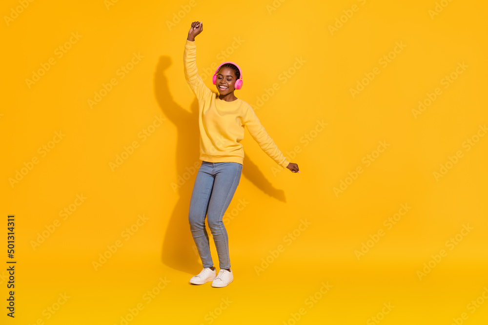 Full length body size view of attractive cheerful dreamy girl fan listening rock dancing isolated over bright yellow color background Full length body size view of attractive cheerful dreamy girl fan listening rock dancing isolated over bright yellow color background