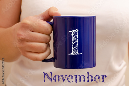 The inscription on the blue cup 1 november. Cup in female hand, business concept photo