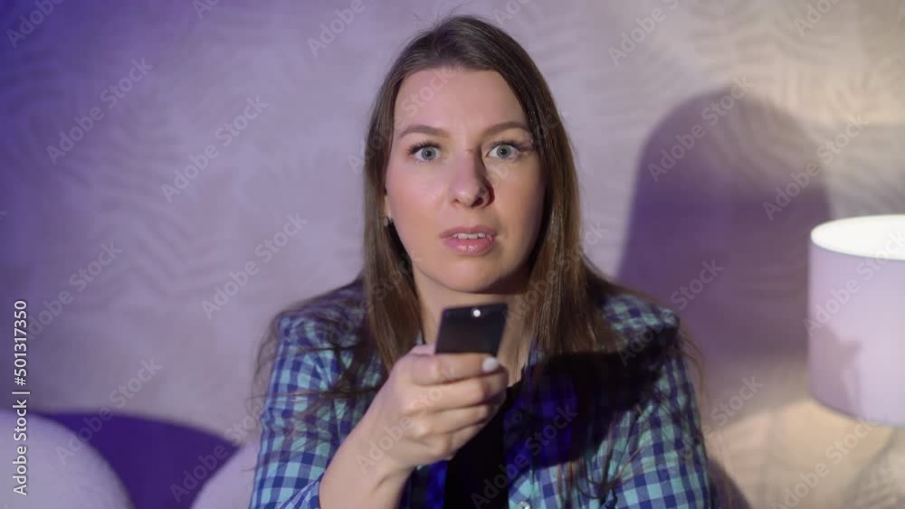 Young woman sits on an armchair and watches TV. Young woman sits on an armchair and watches TV.