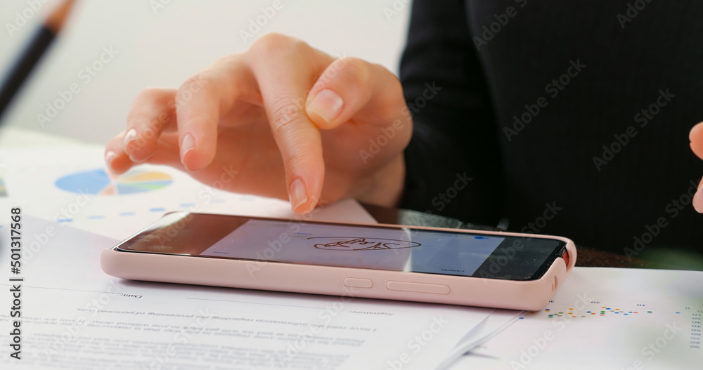 Digital Signature on smartphone screen with woman hand. Sign Document of Deal at Work in Office Indoors. Write Business Agreement for Entrepreneur. Contract electronic signature. Digital Signature on smartphone screen with woman hand. Sign Document of Deal at Work in Office Indoors. Write Business Agreement for Entrepreneur. Contract electronic signature.