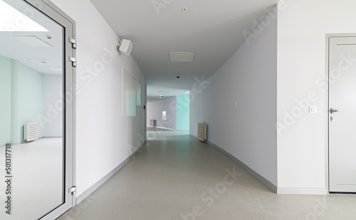 Długi, szeroki i jasny korytarz w obiekcie biurowym.