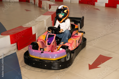 Happy girl driving a toy car. Amusement park for children