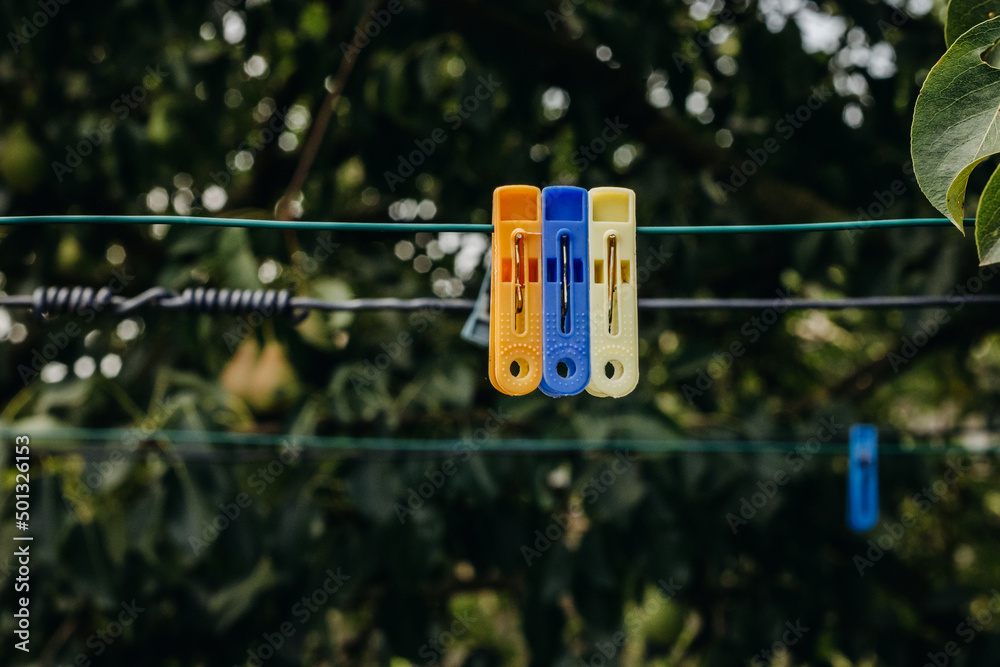 Clothespins on a clothesline in the garden. Colorful plastic clothespins on the hangers with blurred background. Clothespins on a clothesline in the garden. Colorful plastic clothespins on the hangers with blurred background.