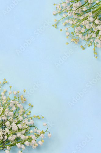 White flowers Lily of the valley ( Convallaria majalis, May bells, may lily ) on a blue paper background with space for text. Top view, flat lay