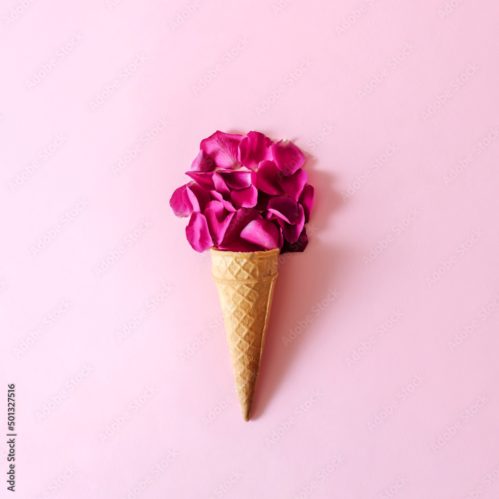 Violet petals arranged in an icecream cone on a pink backgorund. Regreshing floral summer desert concept. Violet petals arranged in an icecream cone on a pink backgorund. Regreshing floral summer desert concept.