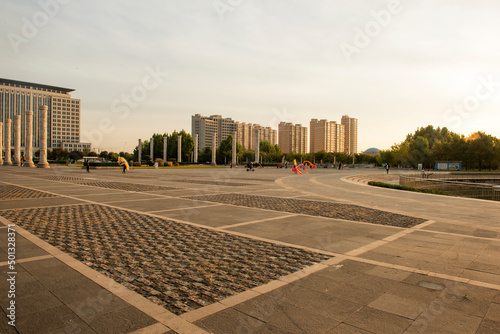 When the sun rises in the morning, the ground of the city park square and the people doing morning exercises photo
