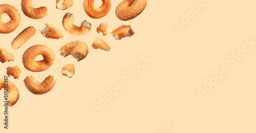 Creative food, baking layout. Fresh round wheat bagel with sesame seeds flying on beige background. Crispy bread, healthy organic food, traditional pastries, bakery product. Breakfast bagel photo