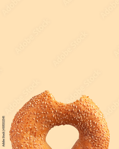 Quadro su tela Fresh bitten round wheat bagel with sesame seeds isolated on beige background