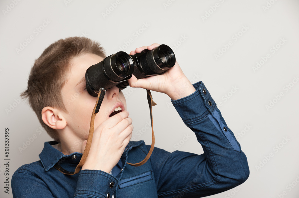 The boy makes observations looking through binoculars