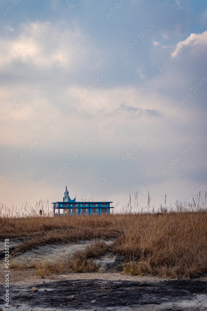 Obraz premium isolated church at yellow grass field with dramatic sky at morning from different angle