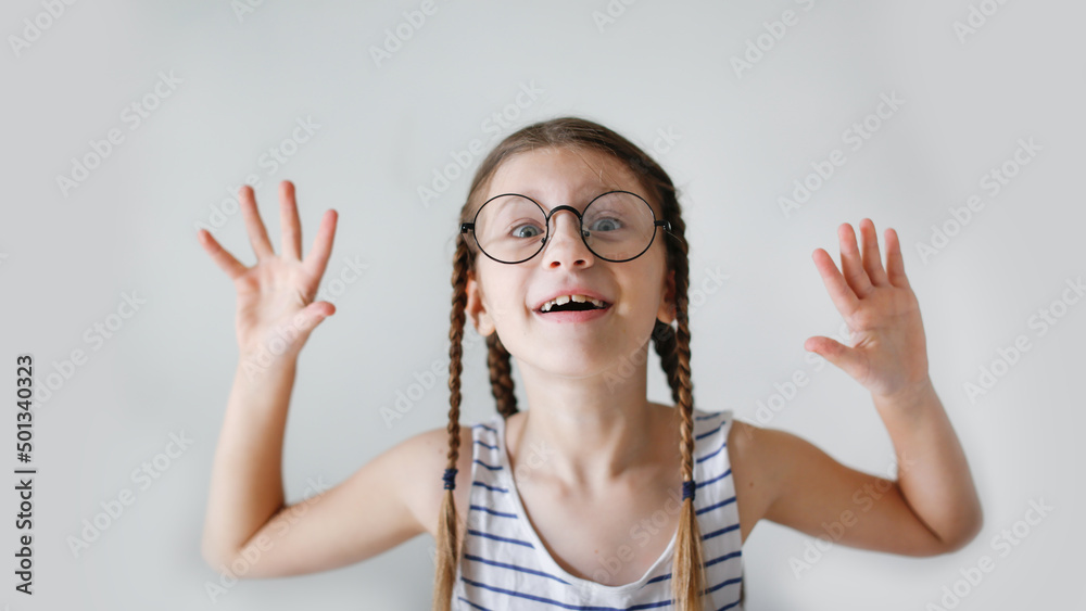 Funny crazy girl child schoolgirl with pigtails in round glasses with hands, copy space and light beige background Funny crazy girl child schoolgirl with pigtails in round glasses with hands, copy space and light beige background