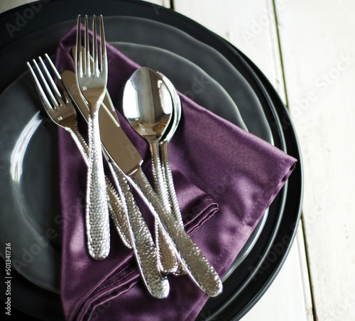 Stack of plates with silk napkins and silverware
