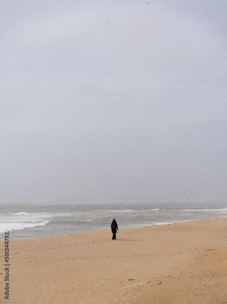 someone walking alone on the beach on a foggy day with a mobile phone