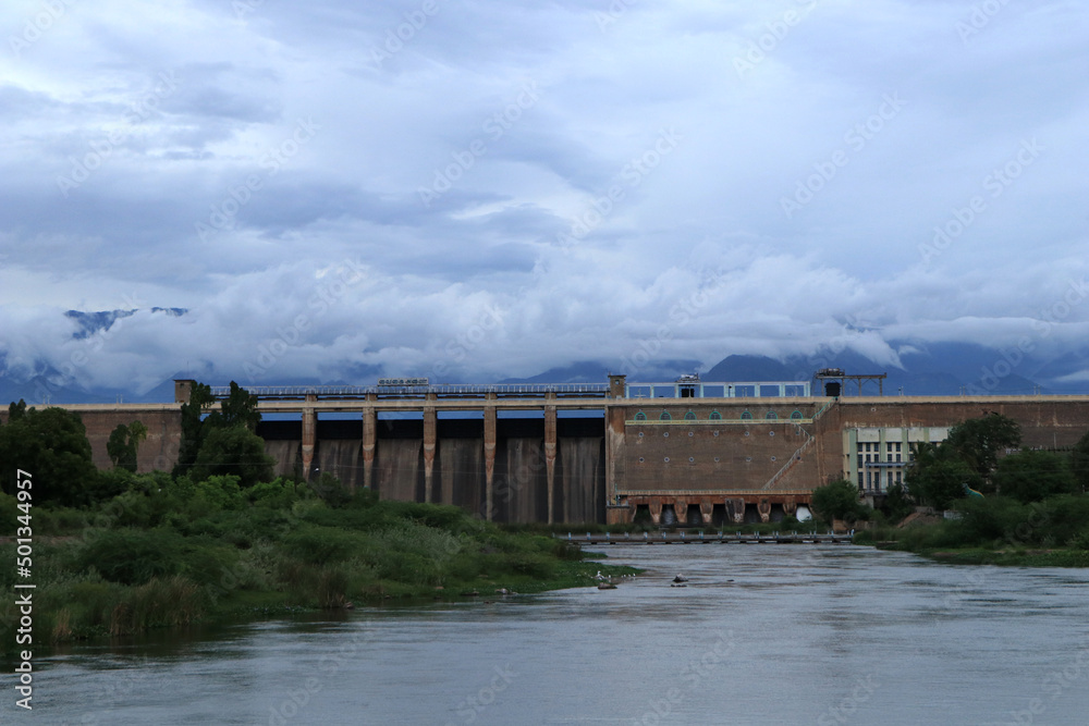 A water reservoir surrounded by the beauty of the clouds, mountains, and trees 