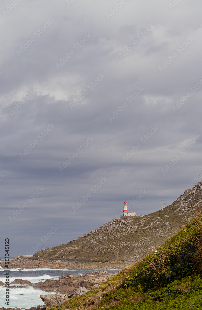 red and white lighthouse in the background on a Rocky Mountain next to the sea 