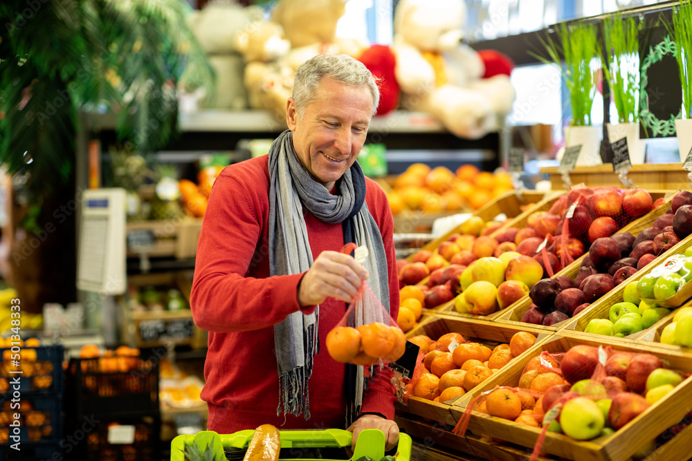 Male customer purchasing at supermarket, choosing fruits