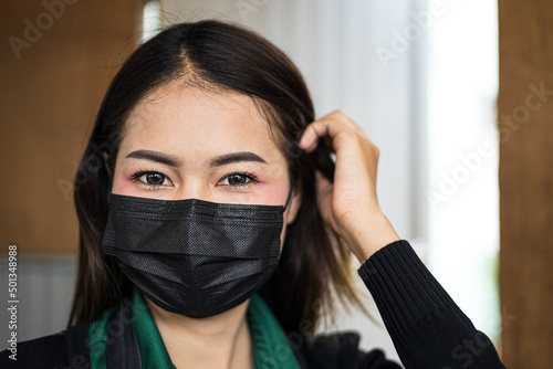 Close-up portrait of a seductively beautiful Thai woman wearing a long-sleeved T-shirt and a black mask.