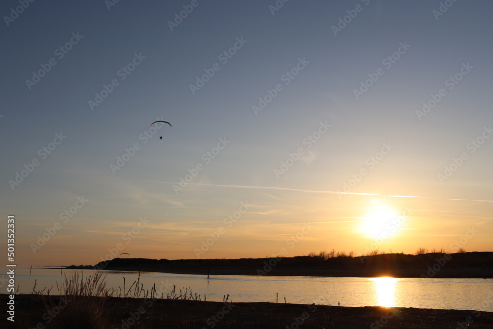 Einsamer Paragleiter fliegt in den Sonnenuntergang Einsamer Paragleiter fliegt in den Sonnenuntergang