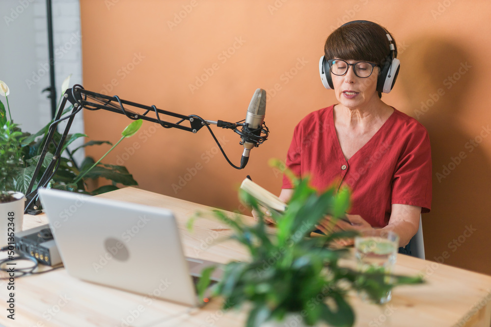 Middle-aged female radio presenter talking into the microphone and reading news - radio broadcast online concept