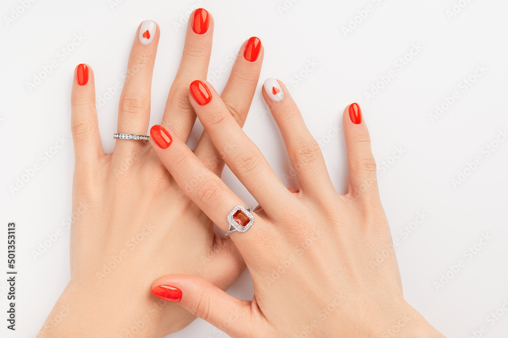 Womans hands with fashionable red manicure on white background. Summer nail design with heart Womans hands with fashionable red manicure on white background. Summer nail design with heart