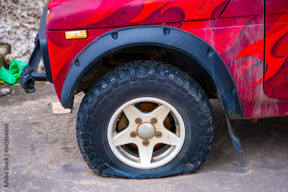 Punctured anterior car wheel on the road, flat car tire close-up. Accident, emergency stop. Punctured anterior car wheel on the road, flat car tire close-up. Accident, emergency stop.