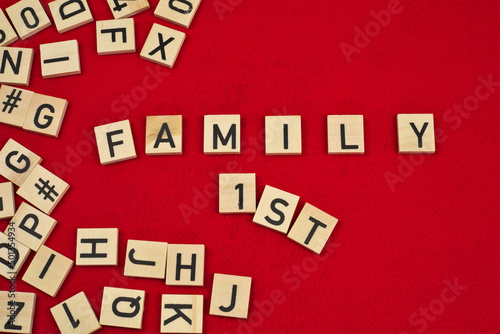 "Family 1st" phrase on a red felt background surrounded by wooden letter tiles