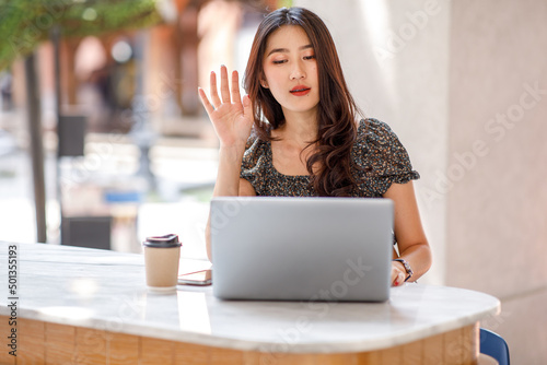 Happy Young Asian woman using a laptop computer at the cafe table Outdoors coffeehouse