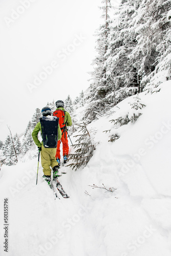 rear view of skiers with backpacks walking on a snow-covered mountain path