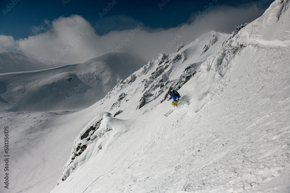Freeride skier rides down the slope at awesome winter landscape background