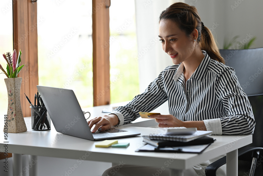 Young Asian woman holding credit card and using laptop computer for internet banking or online shopping, e-commerce, cashless social, business and financial concepts. Young Asian woman holding credit card and using laptop computer for internet banking or online shopping, e-commerce, cashless social, business and financial concepts.