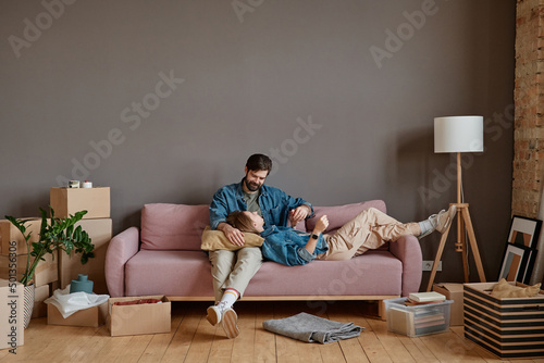 Young man and woman in love relaxing together on sofa in loft living room after moving to new house
