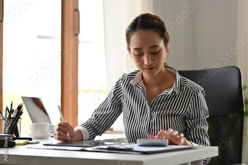 Asian working women sitting in the office while using calculator for accouting, Business and financial concepts. photo