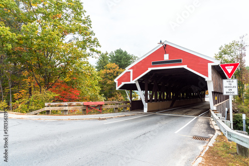 Traditional red covered bridge in New England on a cloudy autumn day
