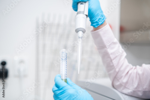 Scientist collects the sample using automatic pipette. Chemical and clinic analysis concept. 