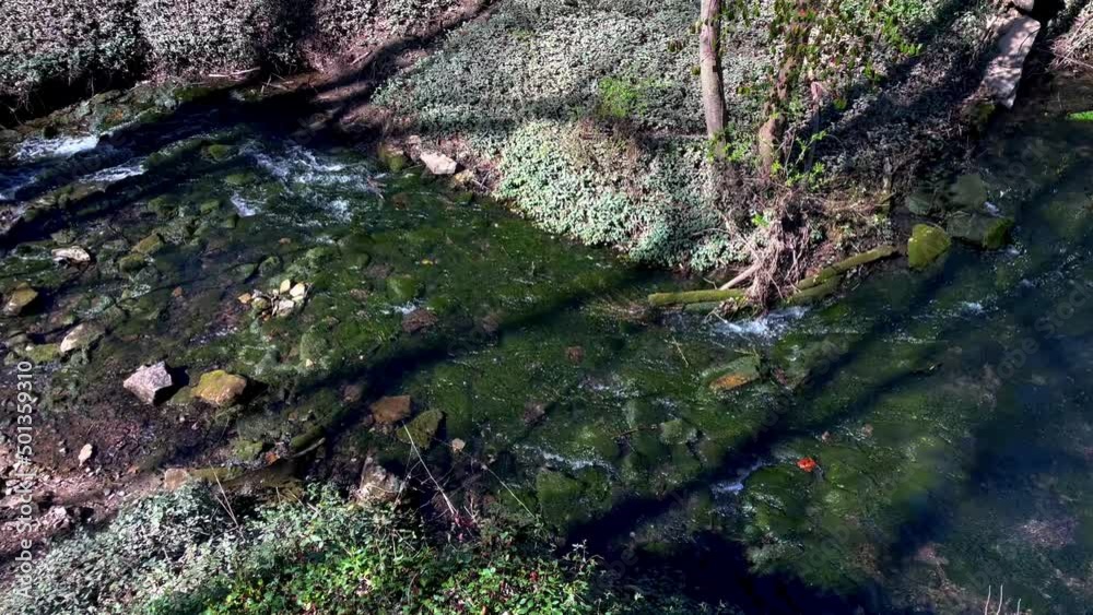 Peaceful beautiful stream of water flowing across the rocks to underground aquifer slow panning Peaceful beautiful stream of water flowing across the rocks to underground aquifer slow panning
