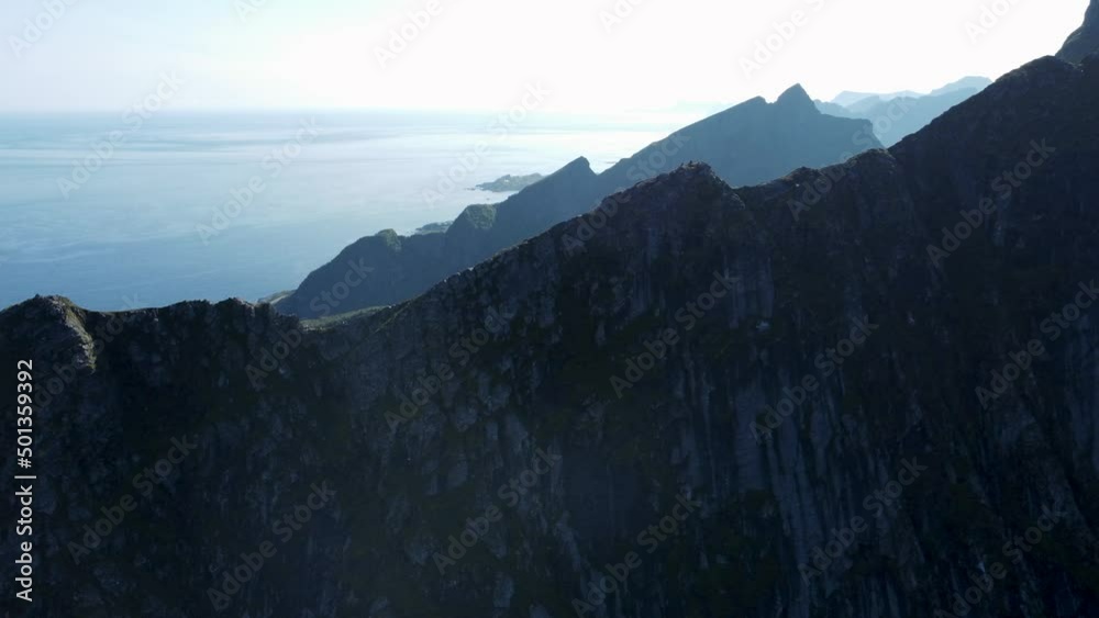 Flying along the chine of a mountain (Reinebringen, Norway) looking at the mountains and the ocean in the background.