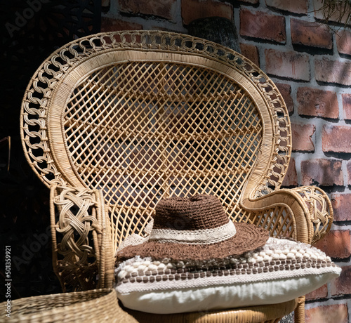 Cozy summer garden chair in rattan and in soft morning light on the terrace  inviting to relaxation. Shallow depth of field.