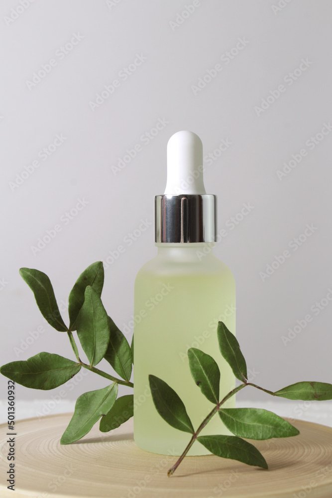 Glass bottle with serum and leaves on marble background. Glass bottle with serum and leaves on marble background.