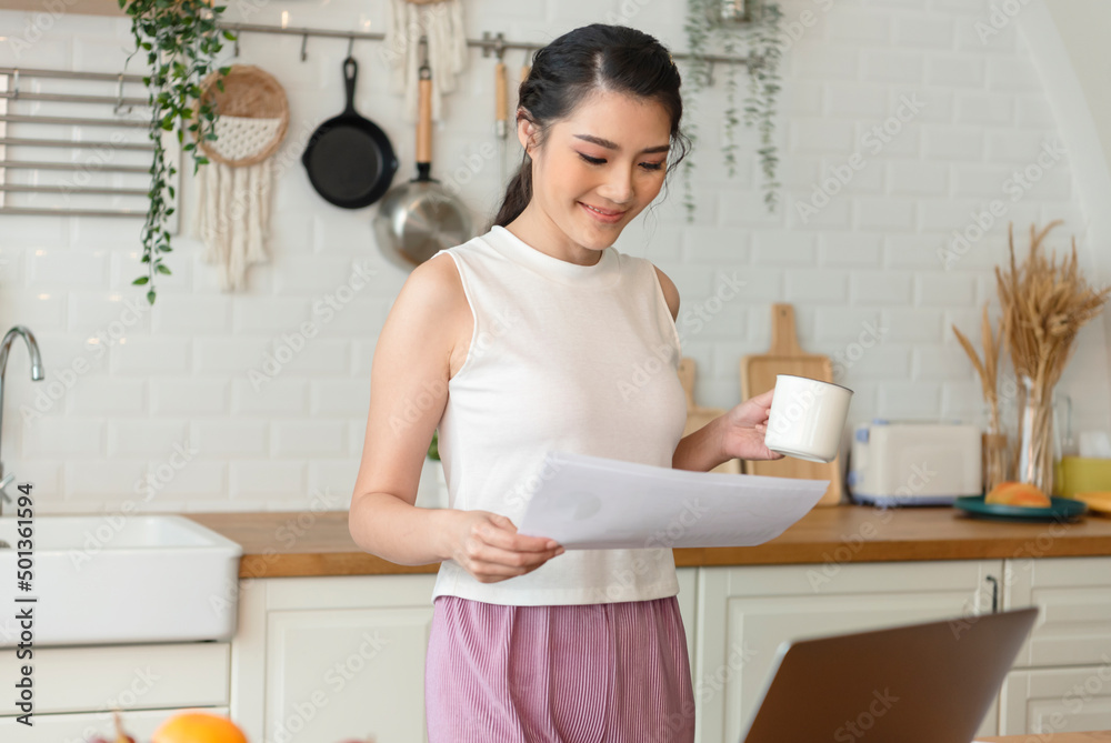 Beautiful young asian woman working at the kitchen room, drinking coffee. Beautiful young asian woman working at the kitchen room, drinking coffee.