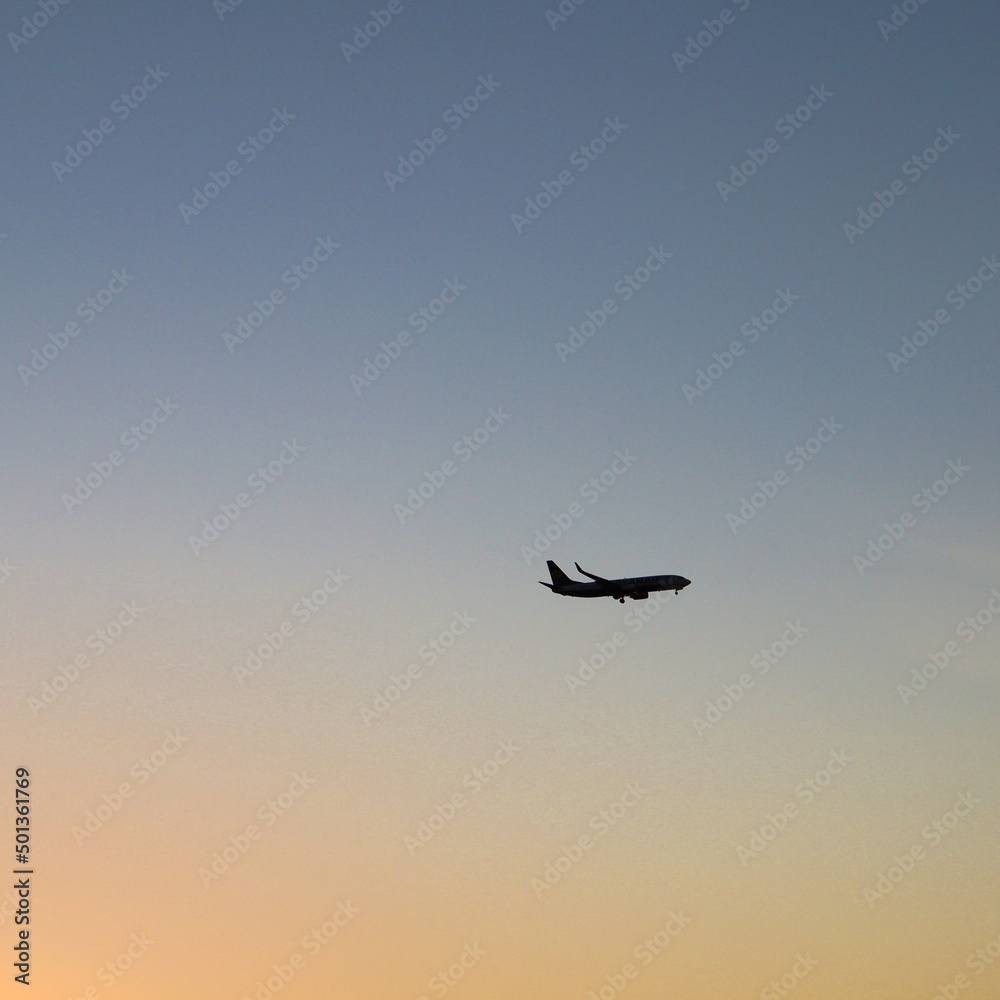 Zarys samolotu w oddali na tle nieba podczas zachodu słońca - obrazy, fototapety, plakaty 