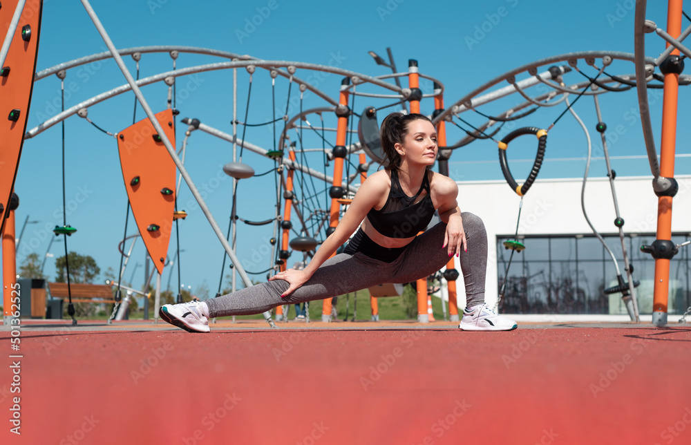 a sporty girl does fitness on a sports field in the summer outdoors