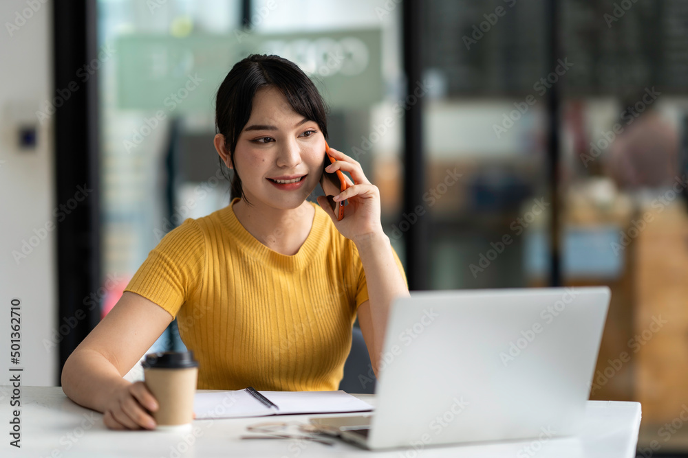 Asian businesswoman is happy and cheerful while using her smartphone and working in the office. Asian businesswoman is happy and cheerful while using her smartphone and working in the office.