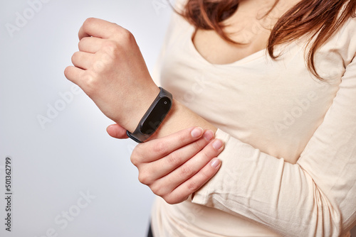 The girl puts on a fitness bracelet. Modern gadgets and digital technologies in human life.