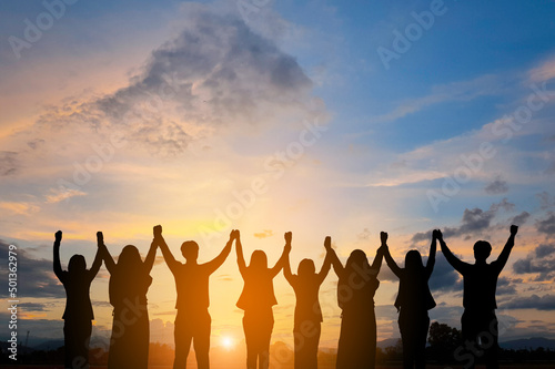Silhouette of happy business teamwork making high hand over head standing back side on sunrise background, friendship,victory,cooperation,goal achieve,copy space.