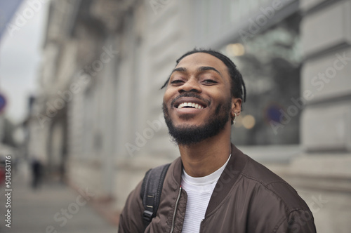 young smiling man with backpack in the street