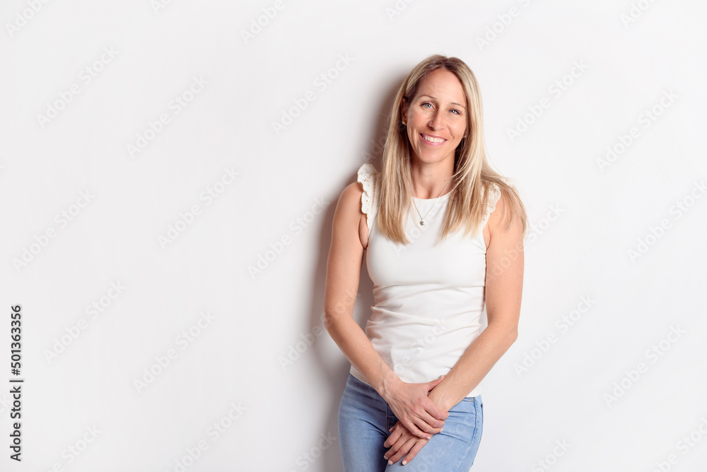 Happy carefree woman with joyful expression, smiling while standing in relaxed pose against white background Happy carefree woman with joyful expression, smiling while standing in relaxed pose against white background