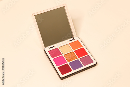 The concept of brand presentation and packaging with a mirror. A makeup palette floating on a white background. Professional multi-color eyeshadow palette with mirror. Cosmetic products. Close-up.